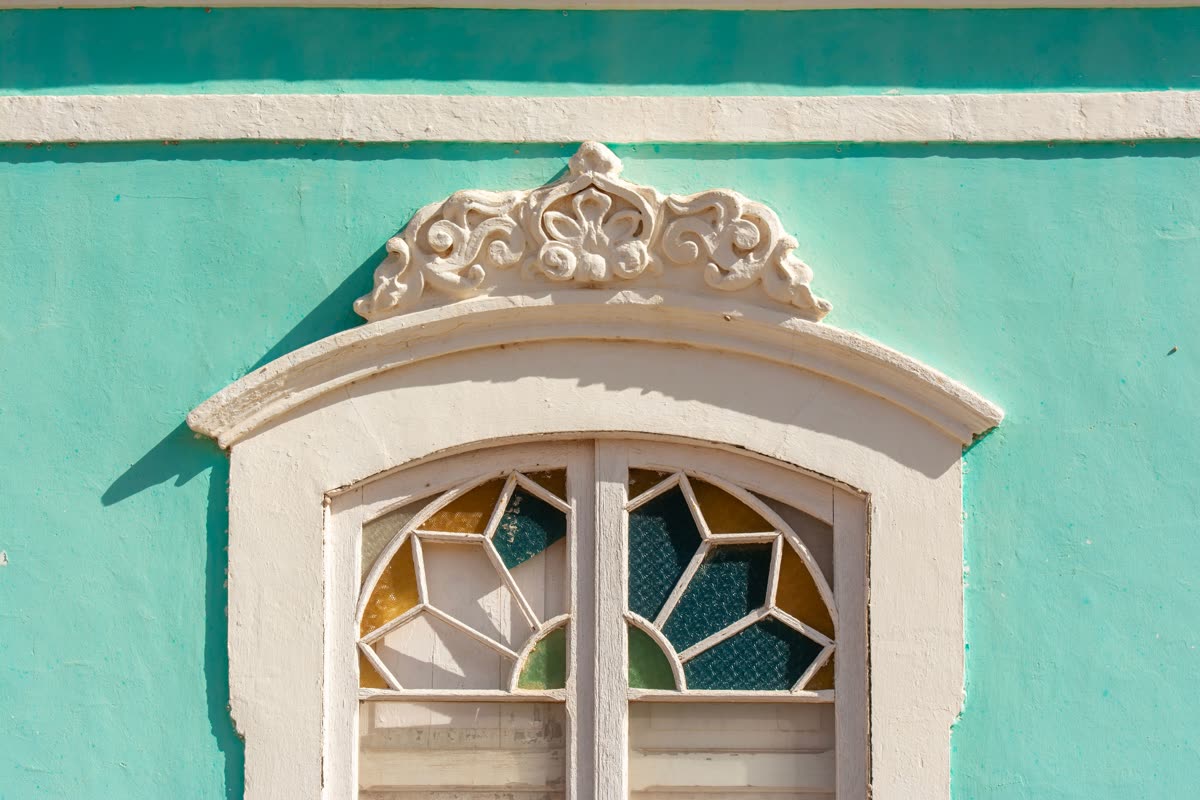 Ornate exterior window trim on a turquoise facade